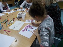 Dzieci siedzą przy stole i wykonują prace plastyczną