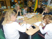 Dzieci siedzą przy stole i wykonują prace plastyczną