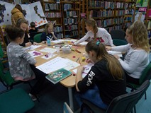 Dzieci siedzą przy stole i wykonują prace plastyczną