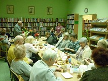 na zdjęciu zebrali siedzą przy stołach i rozmawiają