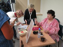 Pani Barbara Li-Przywara siedzi przy stole, wokół niej uczestnicy spotkania.