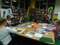 Dzieci siedzą przy stole i wykonują prace plastyczną