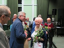 Ewa Maliszewska, z bukietem róż w ręk,u przyjmuje gratulacje