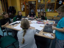 Dzieci siedzą przy stole i wykonują prace plastyczną