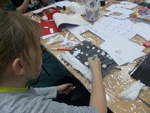 Dzieci siedzą przy stole i wykonują prace plastyczną