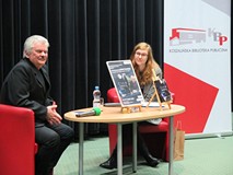 Od lewej: Przy stoliku na czerwonych krzesłach siedzą: Bogusław Janiczak oraz Natalia Wieszczycka. P