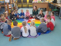 Dzieci siedzą w kole i rozmawiają z bibliotekarką