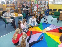 Bibliotekarka czyta dzieciom scenkę w bibliotece szkolnej