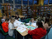 Dzieci siedzą przy stole i wykonują prace plastyczne