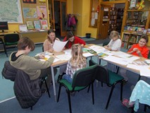 Dzieci siedzą przy stole i wykonują prace plastyczne