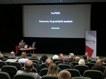 Na pierwszym planie publiczność zgromadzona na spotkaniu ze Stasią Budzisz. W głębi autorka siedzi p