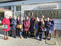Bibliotekarki powiatu koszalińskiego pozują do zdjęcia przed budynkiem biblioteki na tle płaskorzeźb