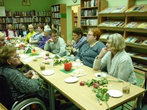 na zdjęciu zebrani siedzą przy stołach i rozmawiają