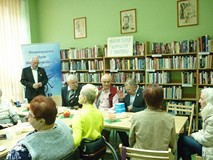 na zdjęciu zebrani siedzą przy stołach i rozmawiają