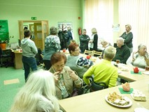 na zdjęciu zebrani siedzą przy stołach i rozmawiają