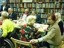 na zdjęciu zebrani siedzą przy stołach i rozmawiają