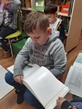 Stary Koszalin i ten współcześniejszy, chłopiec przygląda się ilustracji w książce
