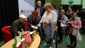 Tydzień Bibliotek 2019. Jakub Żulczyk składa dedykacje po zakończonym spotkaniu autorskim.