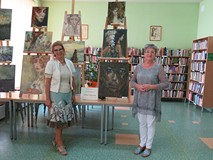 na zdjęciu artystka i kierownik filii stoją na tle obrazów