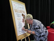 Pani Wanda Kamyk podpisuje sie na plakacie Narodowego Czytania