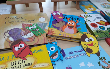 Dziecięce książki na których leża wykonane z paieru kolorowe stworki.
