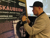 Eskaubei podpisuje się na plakacie promującym wydarzenie