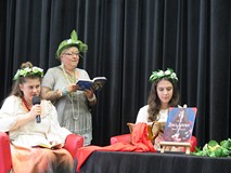 Na zdjęciu: Na scenie trzy panie w kolorowych wiankach i kapeluszu  czytają fragmenty Balladyny Juli