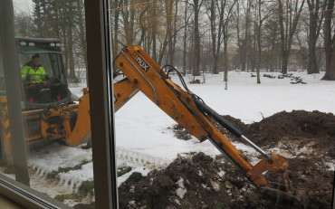 Praca koparki za oknem czytelni głównej KBP. Widok przez szybę od strony czytelni.