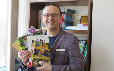 Dyrektor KBP, Dariusz Pawlikowski trzyma w rękach książki o kwiatach