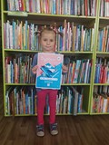 Zosia stoi przy regale z książkami trzymając w rękach swój dyplom