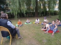 Pani z Ligi Ochrony Przyrody opowiada dzieciom o drzewach i przyrodzie. Wszyscy są w ogrodzie przy b