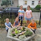 Dzieci stoją wokół gazonu, który samodzielnie obsadzili i udekorowali.