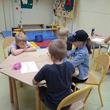 Grupa rozmawiajacych dzieci przy stole.