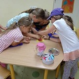 Dzieci przy stole pomagające sobie w szyciu maskotek