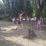 Dzieci i instruktorka tańczą w ogrodzie Zumbę.