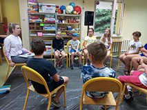 Dzieci podczas zajęć słuchają wskazówek prowadzącej dotyczących kompozycji, kształtów oraz kolorów