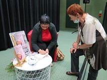 Danuta Rogalska składa autograf na egzemplarzu swojej książki