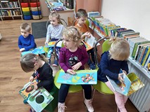 Przedszkolaki oglądają książki, które można wypożyczyć do domu