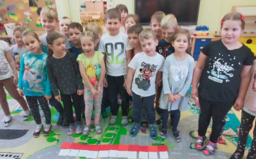Dzieci podczas zajęć prezentują wspólnie ułożoną z karteczek biało-czerwoną flagę Polski