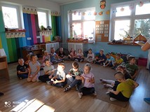 Na zdjęciu przedszkolaki siedzą na podłodze i oglądają zakładki