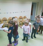 Bibliotekarka wręcza dzieciom kolorowanki