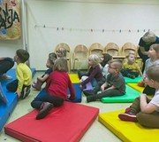 Dzieci podczas zajęć bibliotecznych siedzą na materacach i  rozmawiają  o swoich ulubionych bajkach