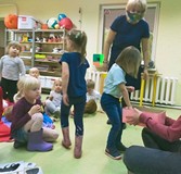 Dziewczynka losuje obrazek z różowego pojemnika; w tle grupa dzieci