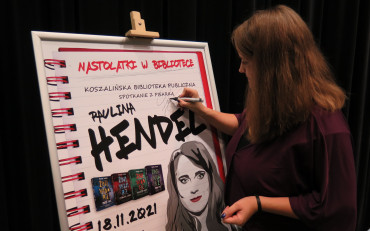 Paulina Hendel podpisuje plakat ze spotkania autorskiego.