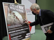 Krzysztof Urbanowicz podpisuje plakat.