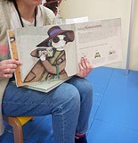 Bibliotekarka czyta dzieciom opowiadania i pokazuje książkę