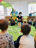 Bibliotekarka prezentuje dzieciom jak wykonać sowę z włóczki.