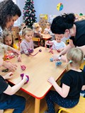 Dzieci pracuja przy stolikach, robią sowę z włóczki