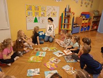 Bibliotekarka pokazuje dzieciom obrazek z postacią bajkową
