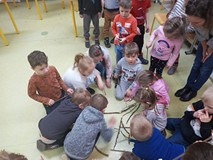 Przedszkolaki układają dinozaura z patyków.